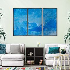 a living room with two white couches and blue paintings on the wall