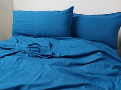 a bed with blue sheets and pillows on it