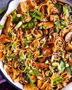 a bowl filled with noodles and vegetables on top of a table