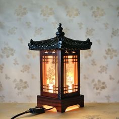 "This amazing carved wooden table lamp features a structure consisting of traditional Korean house windows. When the light is on, each side reveals the design of Sagunja, or \"four noble beings,\" containing four plants, maehwa (spring), orchid (summer), chrysanthemum (autumn) and bamboo (winter) that symbolize the four seasons. This wood lamp has soft and comforting natural light. The Giwa roof is made of resin. light bulb (12E 10W) is included and can be replaced with LED bulbs for brighter li China Lamp, Traditional Korean Home Decor, Korean Cafe Lamp, Korean Hanji Lamps, Antique Korean Furniture, Traditional Korean House, Wooden Accent Table, Red Asian Lamp, Wooden Table Lamps