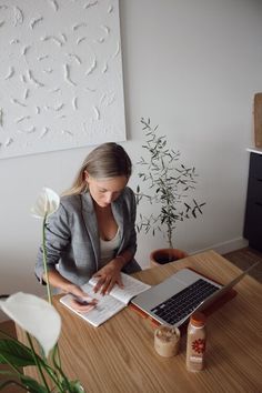 a woman sitting at a table with a laptop and flowers in front of her,