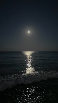 the moon is shining over the ocean at night