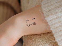 a woman's arm with a cat tattoo on the left side of her arm