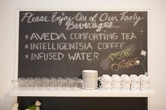 a chalk board with writing on it and cups lined up next to eachother