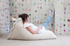 a woman laying on top of a bean bag chair next to a wall covered in polka dots