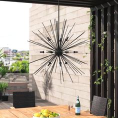 an outdoor dining table with fruit and wine on it, next to a wall mounted sunburst