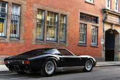 a black sports car parked in front of a brick building