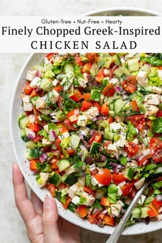 a white bowl filled with chopped greek - inspired chicken salad next to a hand holding a fork