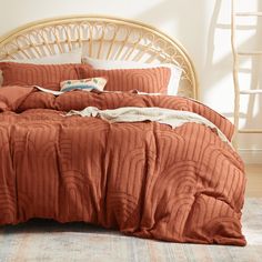 a bed with an orange comforter and pillows