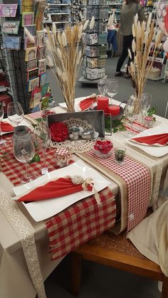 the table is set with red and white checkered cloths, place mats, napkins, silverware, and vases