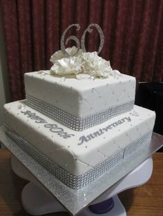 a three tiered white wedding cake with silver decorations on the top and bottom layer