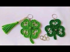 two crocheted shamrock keychains with green tassels on white surface