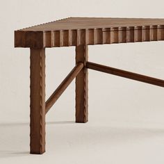 a wooden table that has been made out of wood and is sitting against a white wall