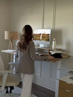 a woman standing in front of a desk with a computer on it