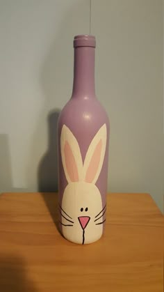 a purple vase with a bunny face painted on it's side sitting on a table