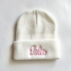 a white beanie with the word julia embroidered on it, sitting on a table