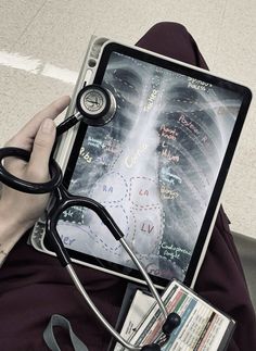 a person with a stethoscope on their lap holding up a tablet