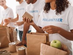 group of people standing around a table with bags and food