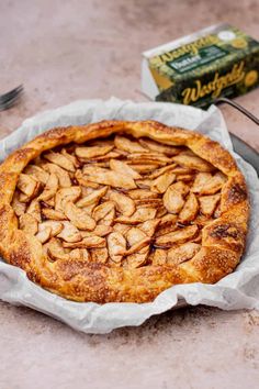 a pie sitting on top of a metal pan next to a box of almonds