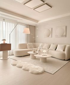 a modern living room with white furniture and rugs on the floor, windows in the background