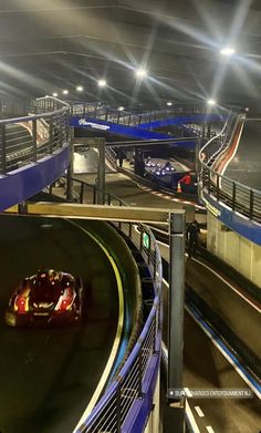 an image of a car driving on a track at night time with bright lights in the background