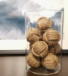 a glass with rope balls in it sitting on a table