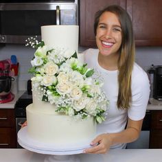 a woman standing next to a cake with flowers on it