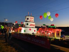 a large cake with balloons and lights on it in the middle of a street at night