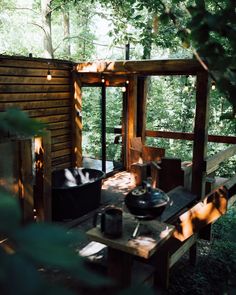 an outdoor kitchen with pot and pans on a wooden table in the shade of trees