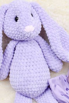 a purple crocheted bunny sitting next to a baby's diaper