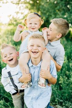 three young boys and one older boy are posing for the camera in front of some trees