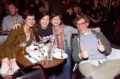 a group of people sitting at a table with drinks and giving the thumbs up sign