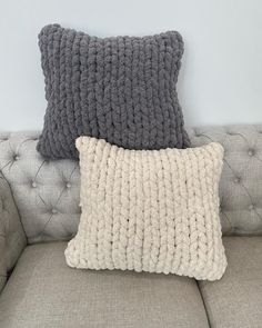 two gray and white pillows sitting on top of a couch