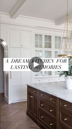 a large kitchen with white cabinets and marble counter tops in front of a chandelier