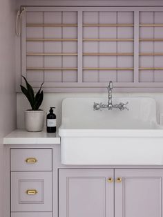 a white sink sitting under a window next to a potted plant in a kitchen