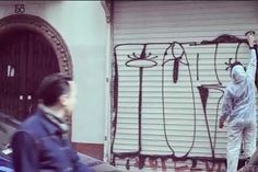 two people walking down the street in front of graffiti on a wall and garage door