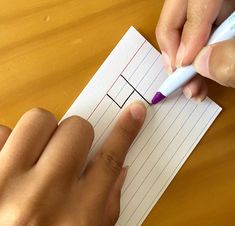 someone is writing on a piece of paper with a pen in their left hand and another person's right hand holding a pencil