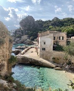 an old stone building sitting on top of a cliff next to the ocean with clear blue water