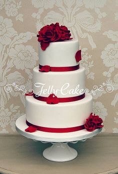 a three tiered cake with red flowers on top