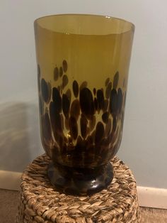 a brown and black glass sitting on top of a wicker basket next to a wall