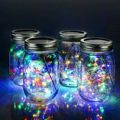 three mason jars filled with colorful lights on a table