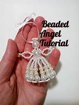 a hand holding a beaded angel ornament