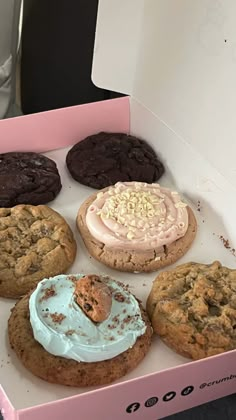 a pink box filled with assorted cookies and frosted cookies on top of each other