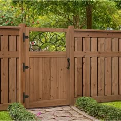 a wooden fence with a gate in the middle and flowers on the ground behind it