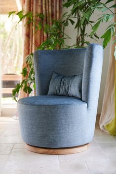 a blue chair sitting on top of a white floor next to a potted plant