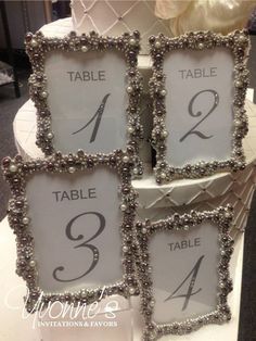 the table numbers are decorated with pearls and beaded trims on this wedding cake