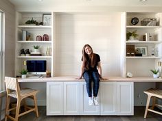 a woman sitting on top of a white desk