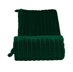 a green blanket sitting on top of a white floor next to a black object with tassels