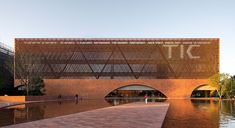 a brick walkway leads to a building that has a water feature in the center and people walking around it