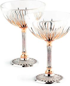 two wine glasses sitting next to each other on a white surface with gold rims